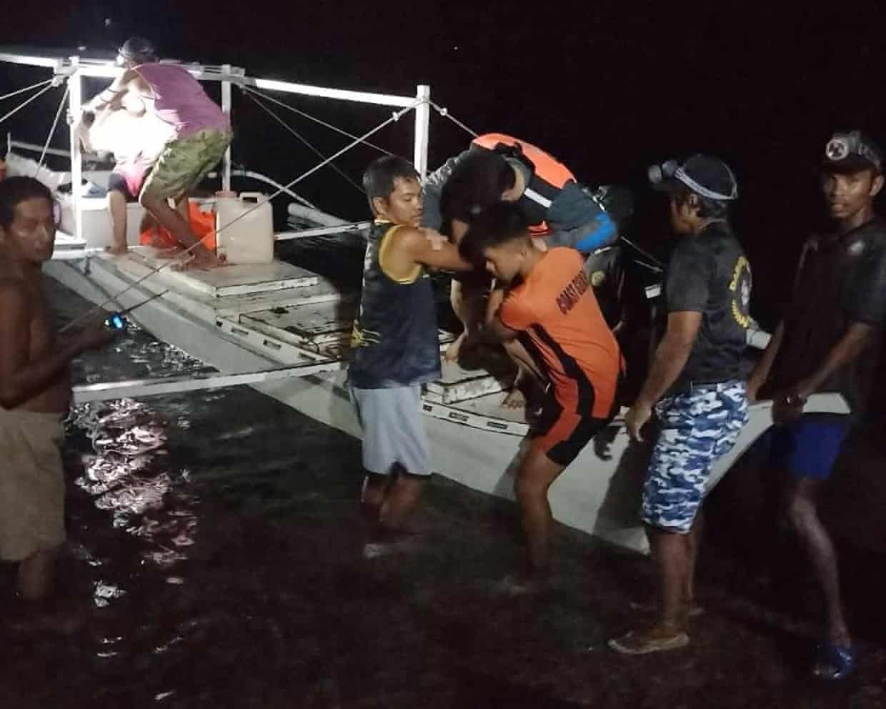 A survivor is assisted as he gets off a small boat after being rescued from the burning ferry
