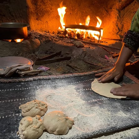 Hands preparing naans beside an open fire.