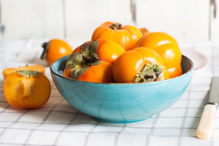 Ripe sweet persimmons in a blue dish.