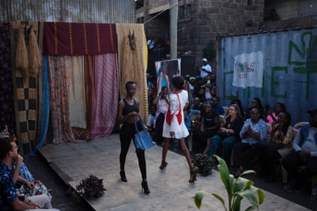 Two women pass on the runway, both holding brightly coloured handbags.