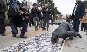 Syria’s negotiating committee spokesman kisses pictures of Syrian victims displayed at the UN in Geneva.
