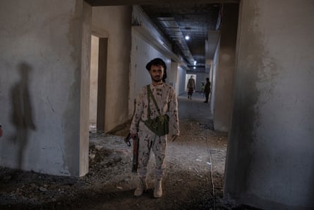 A soldier guards a delegation of foreign journalists at a hospital under construction in Ataq