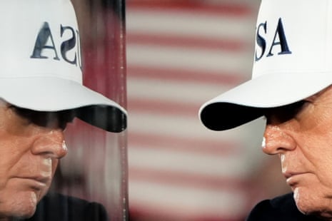 President Trump wearing a white "USA" cap is reflected in glass, his profile shown twice