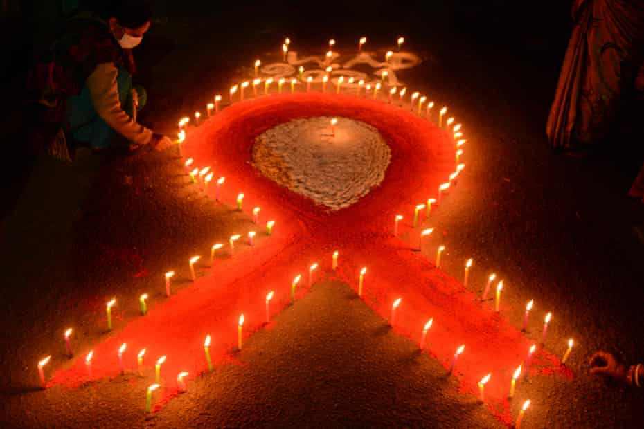 A volunteer lights candles in the shape of a red ribbon at a World Aids Day event, Khalpara, India
