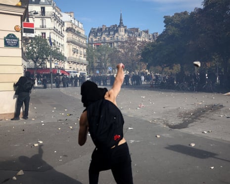 A protester throws stones amid clashes with French riot police in Paris.