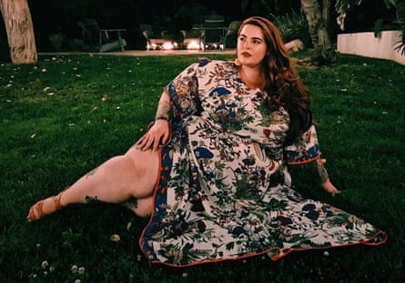 Tess Holliday wearing a floral kaftan sitting on a lawn at night