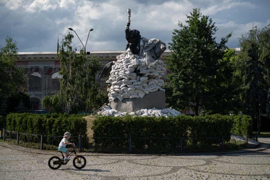 A boy rides a bike next to the Petro Sahaidachnyi monument covered with sand bags in Kyiv, Ukraine.