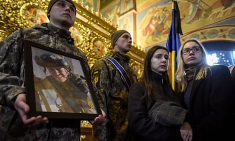 An honour guard soldier holds a portrait of a Ukrainian serviceman at his funeral in Kyiv after he was killed near Bakhmut