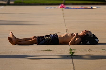 A thin, older man lies with ankles crossed on cement.