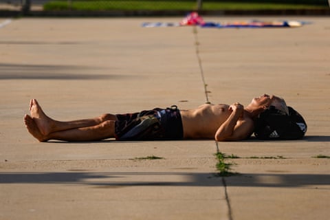 A thin, older man lies with ankles crossed on cement.