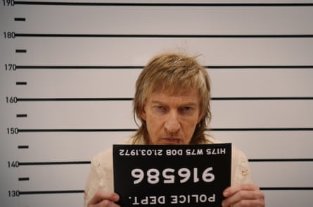 David Wenham in holding up a police number upside down in Spit.
