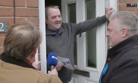 Lee Anderson talking to man on doorstep with another man, back to camera, holding a microphone