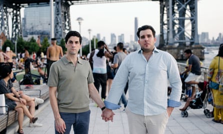 Corey Briskin and Nicholas Maggipinto holding hands in front of a crowd under a bridge by a river in New York