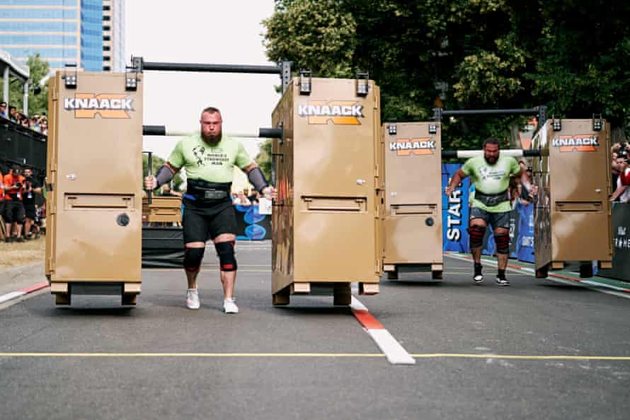 two men walk with large cabinet-like structures on both sides of each of them