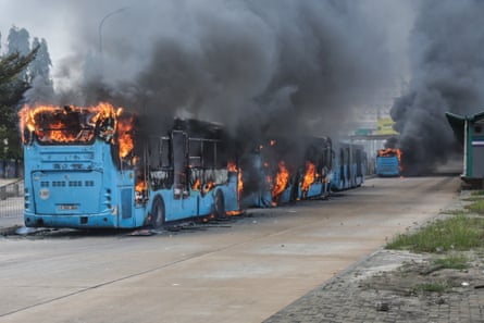 Clouds of black smoke billowing from a row of burning buses