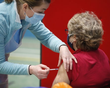 Person receiving a vaccination in the upper arm from an attendant in clinical clothing
