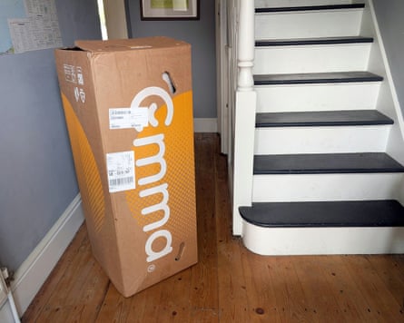 The Emma Hybrid Premium Mattress in a cardboard box in a hallway prior to unboxing.