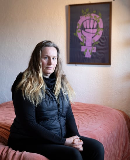 Wilson sits on the bed, behind her a block-print poster depicting a clenched fist