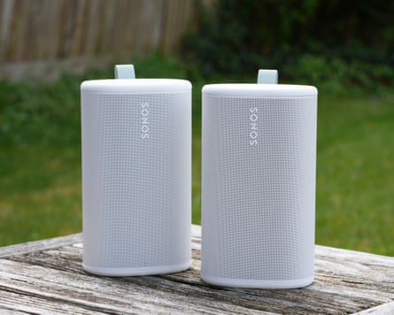 A pair of Sonos Play speakers sitting on a table in a garden.