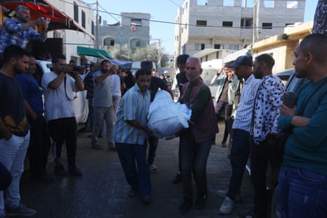 The body of a Palestinian is carried by a group of men to al-Aqsa hospital for funeral procedures after the Israeli army's attack on the refugee camp in al Maghazi.