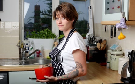 Jack Monroe in 2013, standing in a kitchen wearing an apron