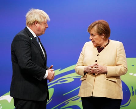 Merkel stands with hands clasped as she speaks to Johnson
