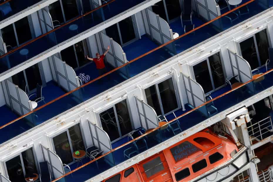 A passenger reacts from his cabin balcony as the Grand Princess docks at the port of Oakland on 9 March 2020.