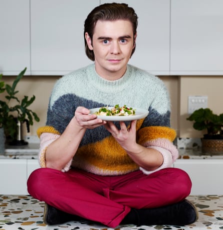 Ryan Riley sitting on kitchen counter holding a plate of his pineapple tacos