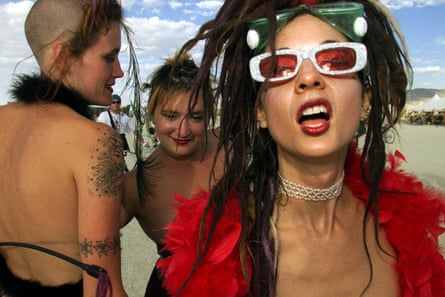 Striking women with shaved heads and 90s attire mug for the camera.