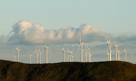 wind turbines on a hill against puffs of clouds in a blue sky