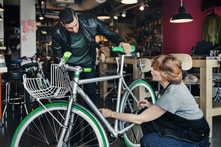Female mechanic analysing bicycle while talking to customer in repair shop