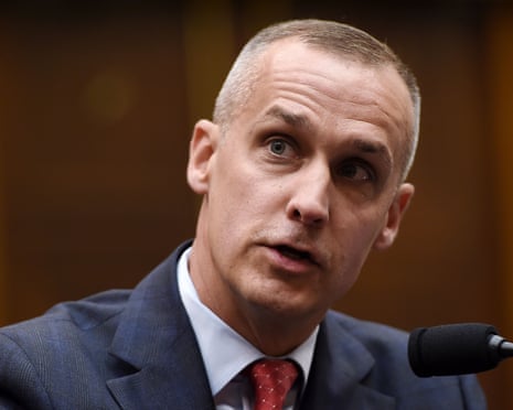 close-up of man wearing gray suit and red tie sitting behind microphone