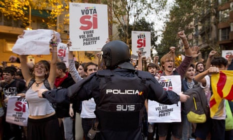A Spanish national police officer tries to stop protesters calling for a referendum in Barcelona, Spain, amid a crackdown that has included the arrests of more than a dozen officials.
