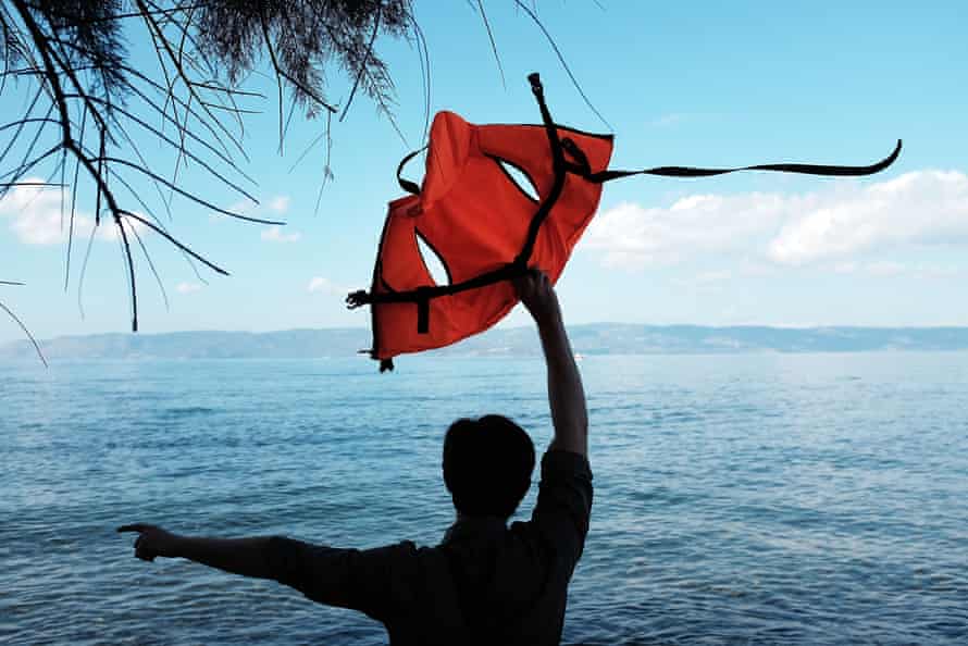 A man uses a life vest to guide a raft carrying Syrian and Iraqi refugees onto the island of Lesbos from Turkey.