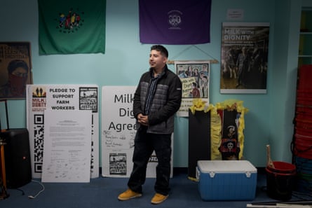 A man in an office with farm workers’ signs and banners behind him