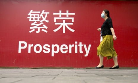 A woman in China passes a red sign marked 'prosperity'