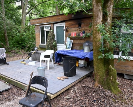 A single-storey wooden shack in woodland