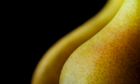 Two perfect pears on black background with warm lighting and shallow depth of field. Shot to resemble the curves of a breast or buttocks