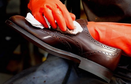 Hands in rubber gloves rub a cloth over a shiny brogue