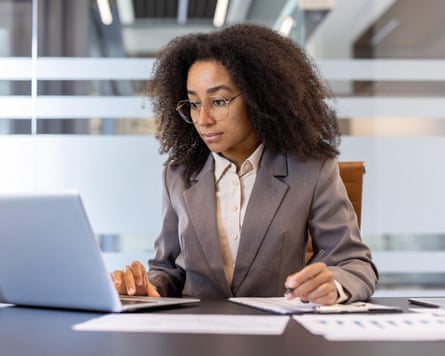 a woman looks at her laptop in an office