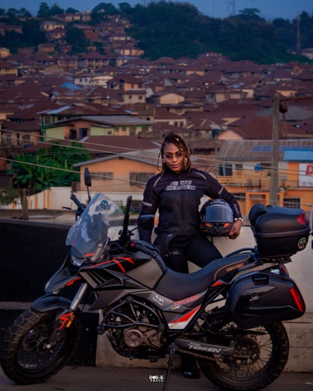 An African woman poses with her motorbike and helmet in a town