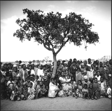 A crowd gathers under a tree as they wait for food distribution at a refugee camp near Cuemba, Angola.
