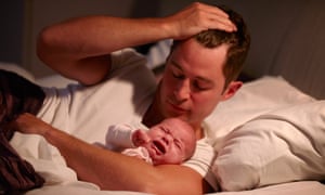 Father lying in bed with crying baby daughter
