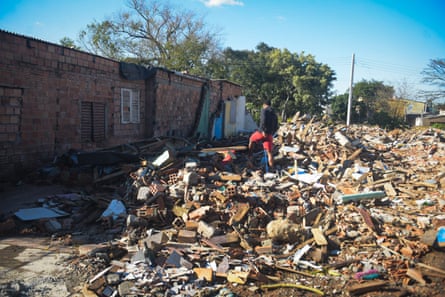 A man walking among the rubble of a house destroyed in the Porto Alegre floods of May 2024.