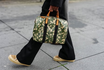 A woman holding a Vuitton camouflage bag with printed monograms