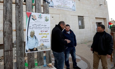 Men stand next to a poster of Omar Abdalmajeed As’ad, 80, in Jiljilya village in the Israeli-occupied West Bank.