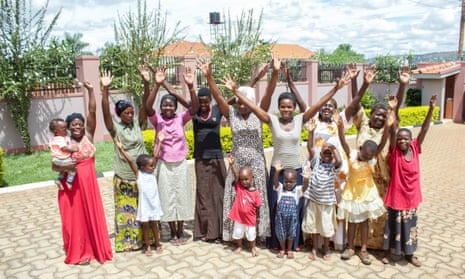 A group of African adults and children wave at the camera for a group photo