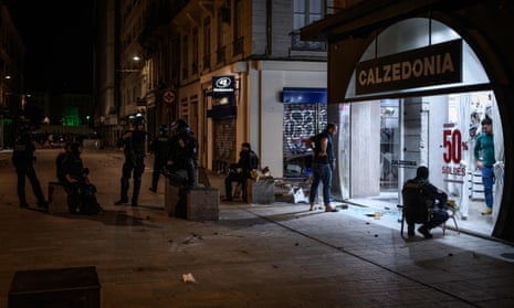 Police in front of a looted store as they patrol Lyon’s streets