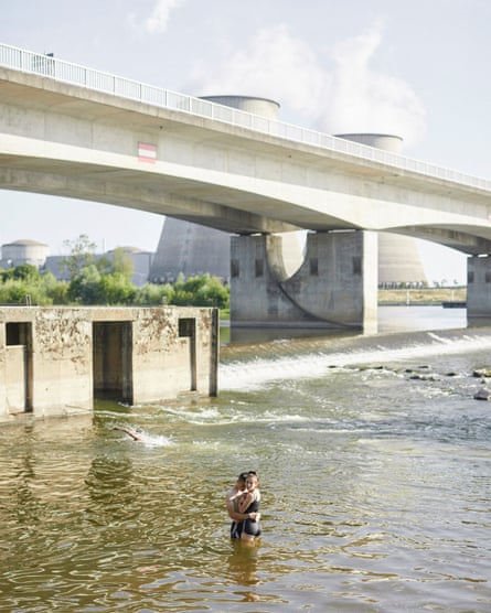 A young couple embrace in the river Loire, opposite the Belleville nuclear power station in Belleville-sur-Loire in central France. The plant uses water from the river to cool the two reactors, which is then ejected as vapour and as water further downstream. Heatwaves, low water levels or high water temperatures can restrict operations at the power station.