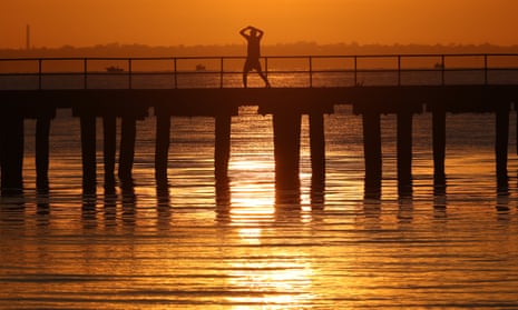 A men stretches during sunrise over Altona pier in Melbourne.